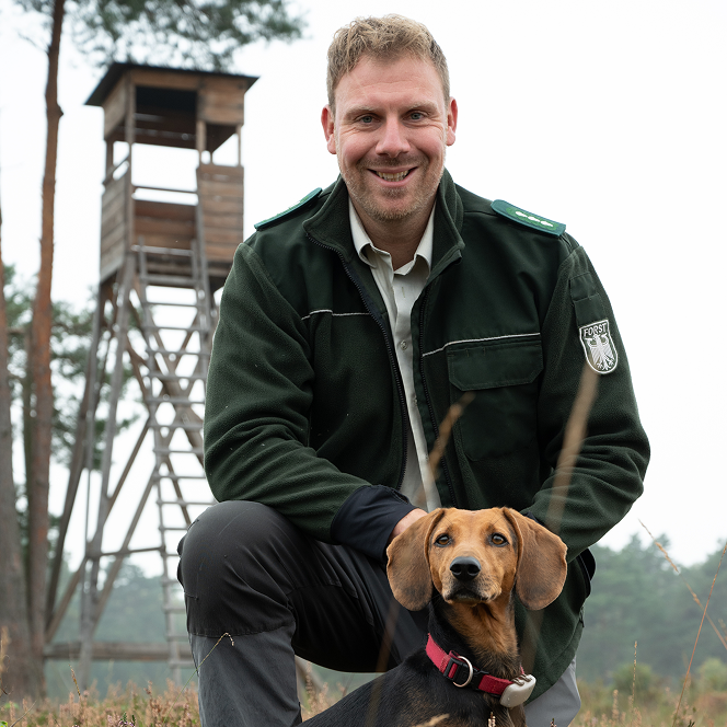 Foto von einem Mann in Forst-Uniform mit einem Dackel.