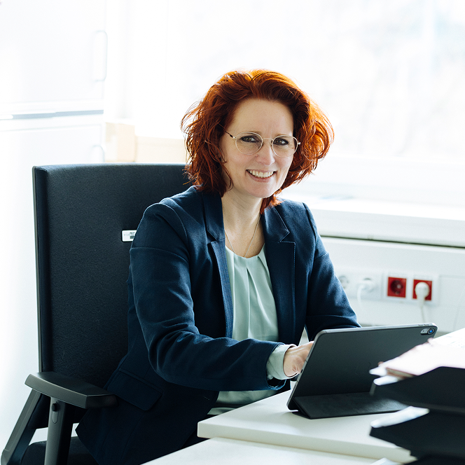 Foto von einer Frau an einem Schreibtisch mit iPad.